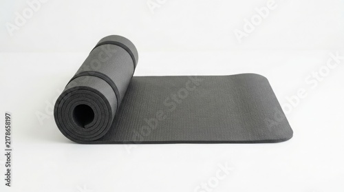 Rolled black exercise mat isolated on white background