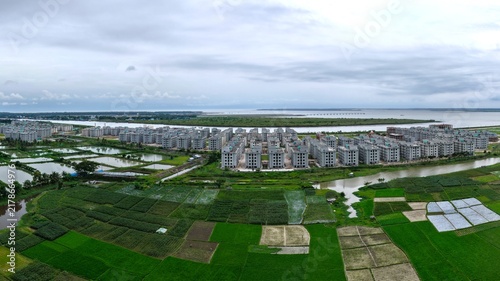 Aerial view of Khurushkul Ashrayan Prokolpo housing project with rows of modern apartment buildings surrounded by green fields and water bodies in Cox's Bazar, Chittagong Division, Bangladesh.