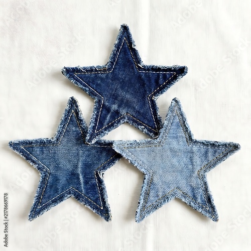 Three denim fabric stars with frayed edges in different shades of blue, arranged in a group, isolated on white background