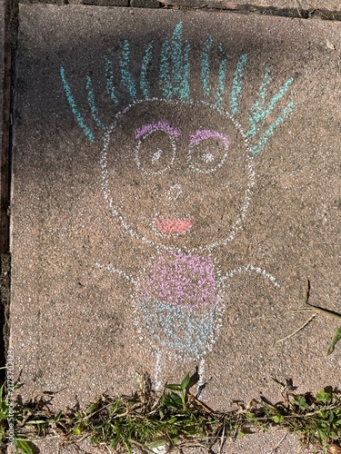 Bonhomme dessiné à la craie sur le sol par un enfant, activité créative en extérieur