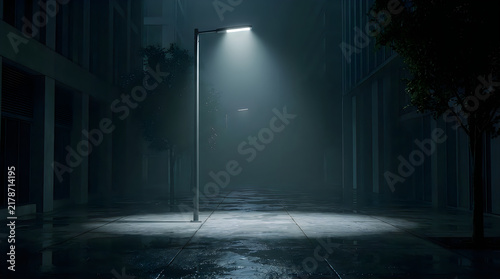 Lone street lamp illuminates a foggy city street at night with wet pavement and building reflections