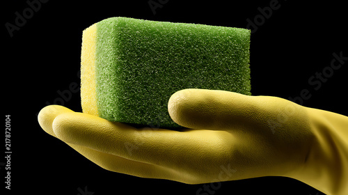 Yellow rubber glove holding a green and yellow cleaning sponge on black