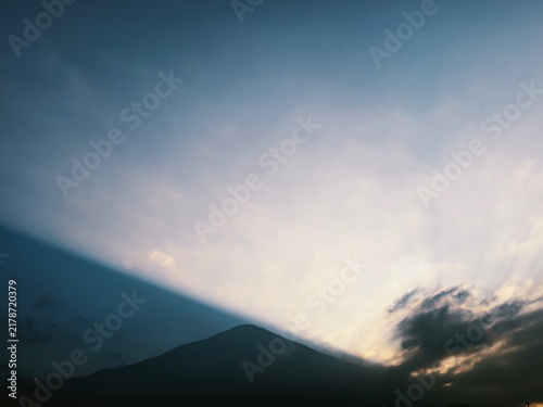 Majestic silhouette of Mount Fuji at dusk with dramatic sunset light and soft clouds in blue sky
