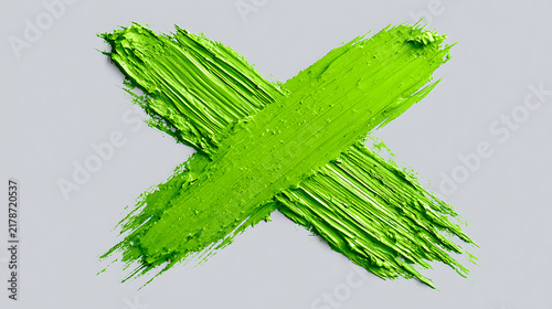 Green paint stroke forming an x mark against a gray background