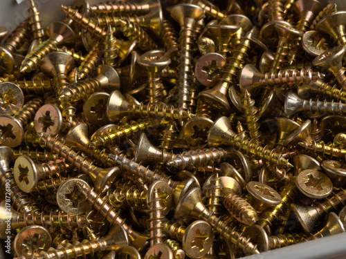 Fotografía Gold Zinc Wood Screws Pile Close-Up - Large pile of gold zinc-plated countersunk Phillips head wood screws filling a storage bin, macro detail view