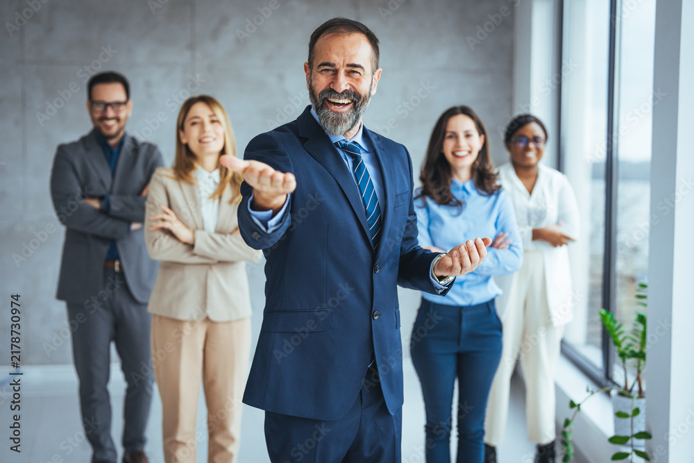 Obraz premium Confident Business Leader Welcoming Team in Modern Office, Diverse Professional Group Smiling Together