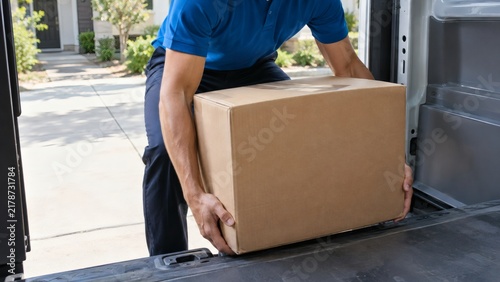 Courier unloading a large cardboard package from a transport vehicle