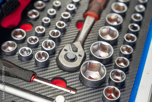 Foto Chrome sockets and ratchet wrench rest in fitted foam storage, with red and black tool handles around them