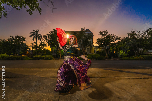 A sturdy Latina-Gypsy woman dancing traditional dances in the streets of Mérida, Yucatán, Mexico; the famous Regional Museum of Anthropology (Palacio Cantón) is visible in the background.
