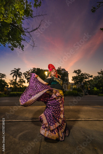 A sturdy Latina-Gypsy woman dancing traditional dances in the streets of Mérida, Yucatán, Mexico; the famous Regional Museum of Anthropology (Palacio Cantón) is visible in the background.
