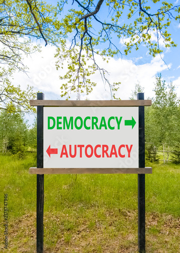 Democracy or autocracy words symbol. Concept words Democracy Autocracy on beautiful white road sign. Beautiful blue sky background. Business democracy autocracy concept. Copy space