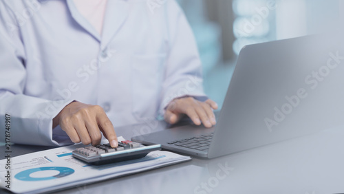 Doctor using calculator to analyze healthcare business data, representing medical growth investment, health insurance cost estimation, financial report, medical business, healthcare budget planning.
