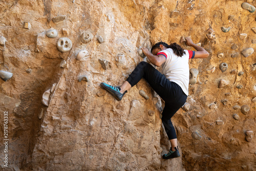 Fotografía Young woman bouldering on a rock climbing wall