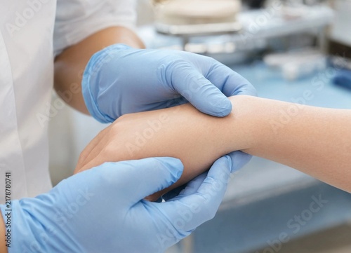 Closeup of healthcare professionals hands wearing blue gloves examining a patients wrist