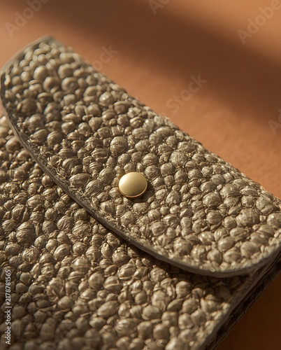 Macro shot of golden textured leather wallet flap with snap closure