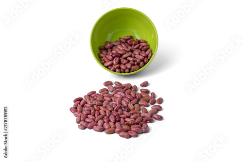 Raw dried red kidney beans spilled from a small bowl on a white background