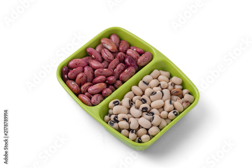 Raw red kidney beans and black-eyed peas in a divided green dish on white background