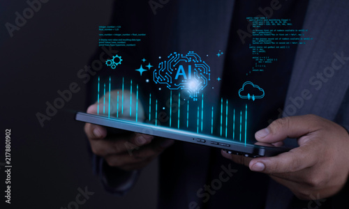 Artificial intelligence and cloud computing concept with businessman hand holding tablet displaying glowing AI brain, cloud network, gears, and digital data graph on dark background.