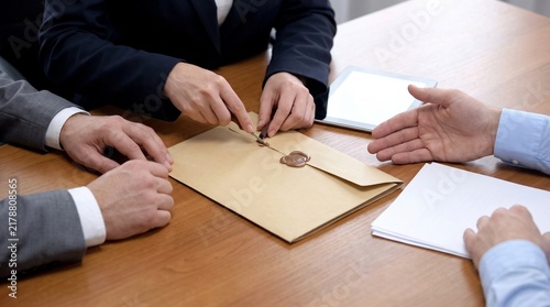 Business meeting with sealed envelope and documents on wooden table