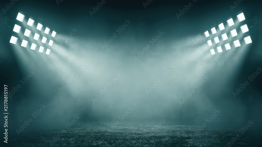 Obraz premium Bright stadium spotlight beams shining through heavy fog on empty dark green turf field.