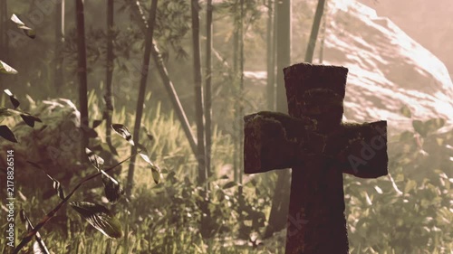 In a serene forest setting, a weathered gravestone stands amidst vibrant greenery. Sunlight filters through the trees, creating a calm and reflective atmosphere.