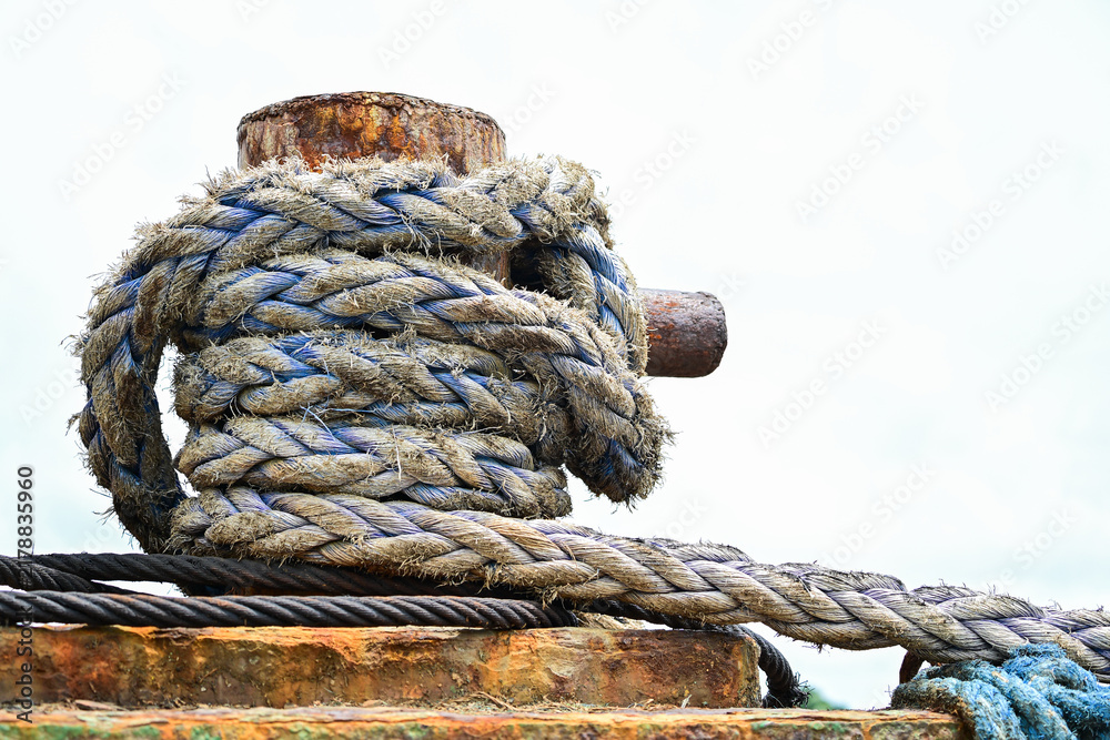 Obraz premium Weathered mooring rope wrapped around a rusty dock bollard on the Iloilo River, Iloilo, Philippines