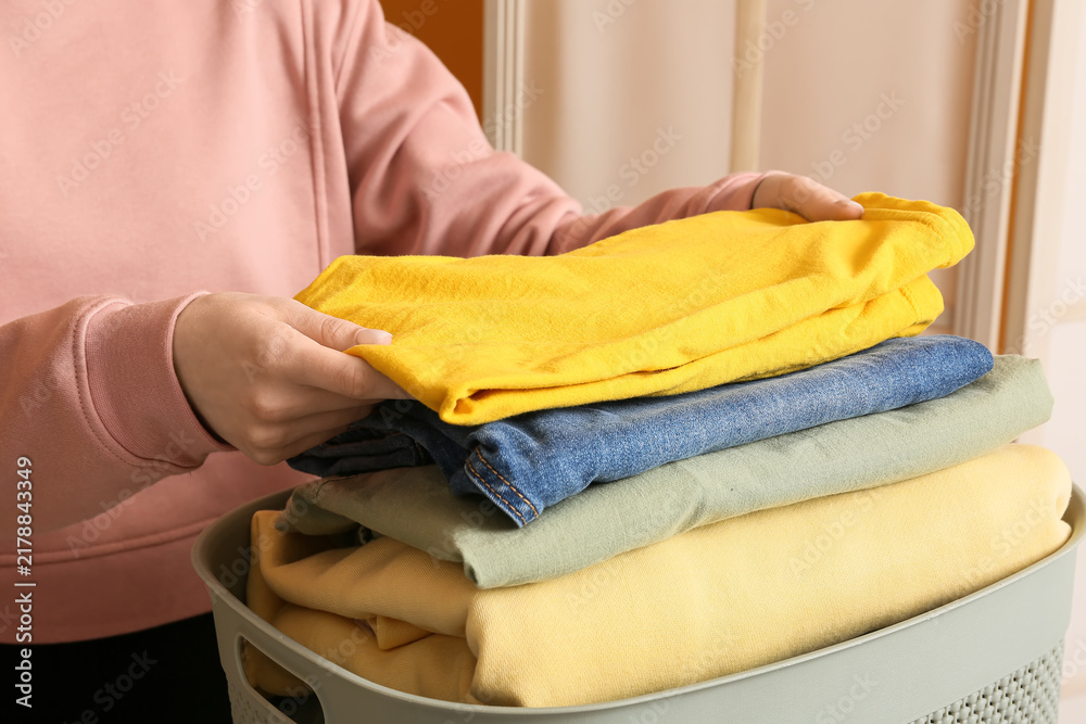 Obraz premium Household chores and laundry organization, person folding clean clothes into a basket for home maintenance and daily routine management in a living space