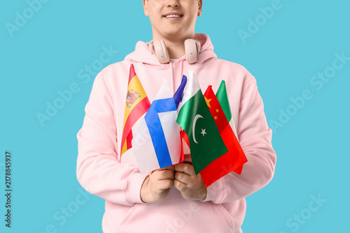 Young happy man with different flags on blue background, closeup