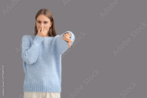 Принти на полотні Young woman feeling disgusting smell and showing thumb-down on grey background