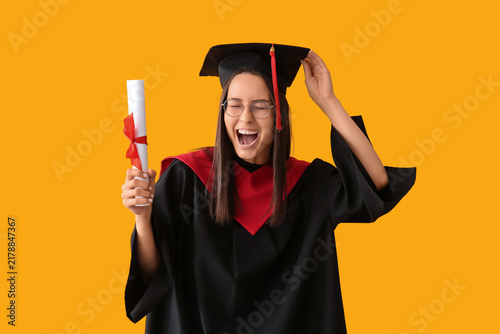 Cheerful female graduate diploma on yellow background