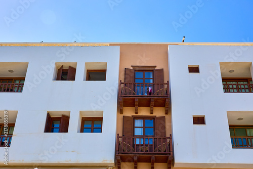 Foto Sunlit Mediterranean-style apartment building with wooden balconies