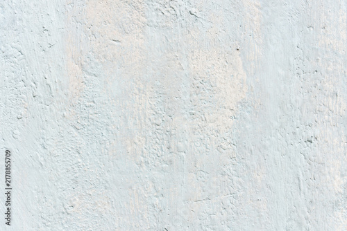 Full-frame texture of a weathered whitewashed plaster wall with distressed paint brush strokes.