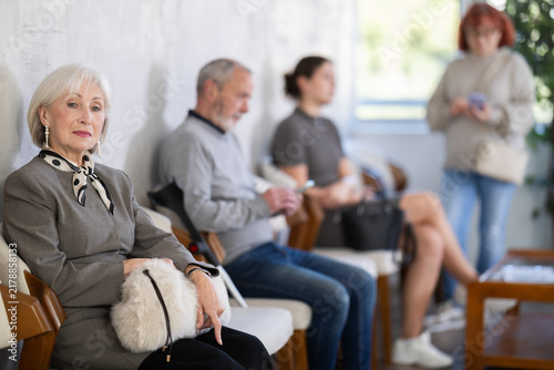 Obraz na plátně Serious senior woman calmly waiting in line at public healthcare facility before