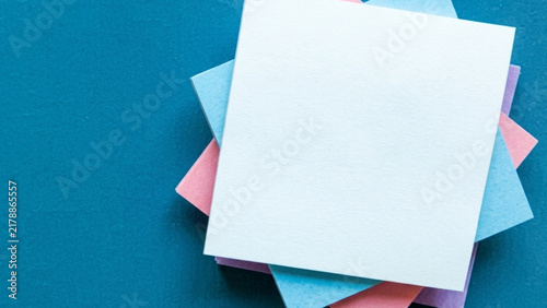 Colorful Stacked Blank Sticky Notes Arranged on a Solid Dark Teal Background for Creative Office Productivity and Organized Planning Concepts