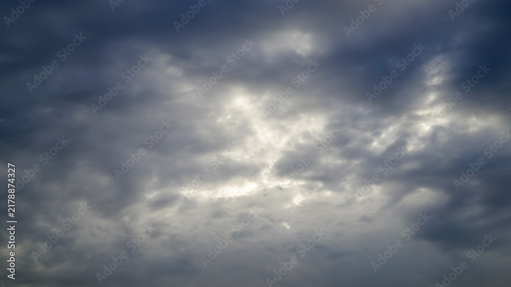 Fototapeta premium heavy grey clouds centered with a bright sunlit gap glowing through the dark sky