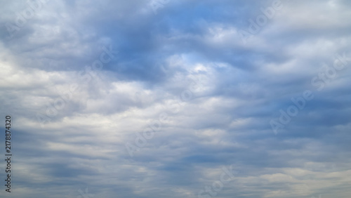 light blue daytime sky evenly covered with soft white and subtle grey cloud layers