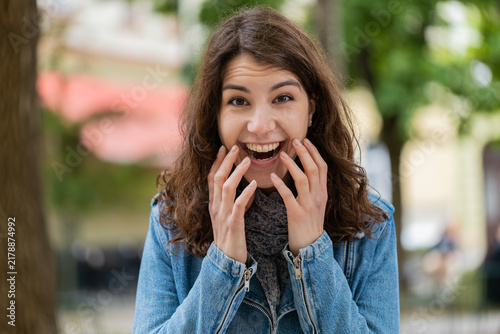 Foto Young woman showing wow reaction while walking in city street with surprised open mouth and true amazement