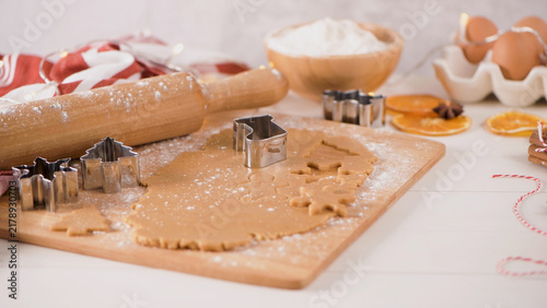 Foto Rolling pin and metal cookie cutters on a wooden board with Christmas dough