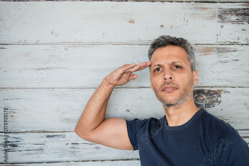 Man Giving Military Salute Gesture Against Rustic Wall