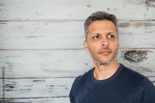 Pensive Man Looking Sideways Against Rustic Wall with Copy Space