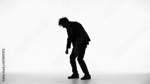 Silhouette Of A Man Standing In A Hunched Sad Pose Isolated On A Bright White Studio Background