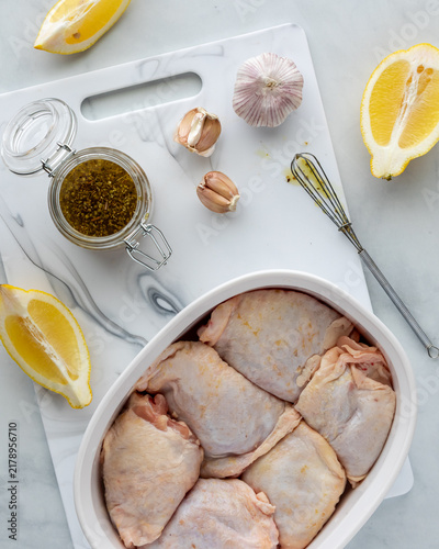 Canvastavla Raw skin-on chicken thighs in a baking dish with marinade and ingredients above