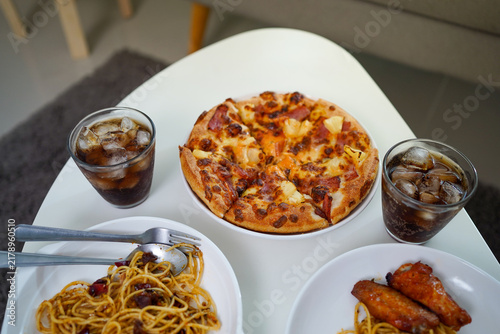 Obraz na plátne High Angle Perspective Shot of Pizza, Spaghetti, Fried Chicken, and Iced Cola on White Table