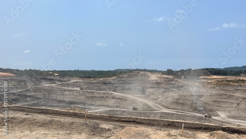 Vast open pit surface mine with dusty excavation terraces and heavy machinery operating