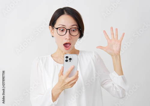 スマホを見て驚くミドル女性　白背景