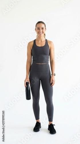 Athletic Woman with Water Bottle in Fitness Outfit on Light Background