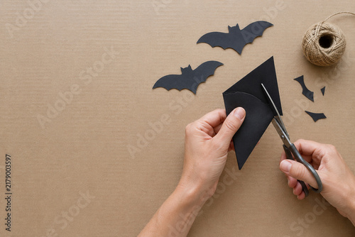Hands Cutting Paper Bats for a Halloween Craft Project