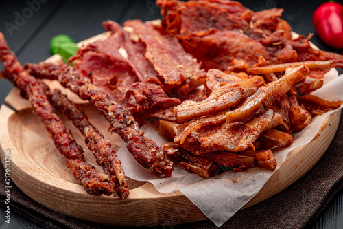 Konstfotografi Meat snacks arranged on a wooden board with spices and peppers