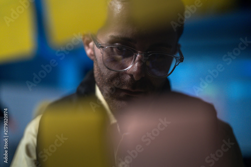 фотографія A bespectacled male planner arranging yellow sticky notes on a glass wall moves