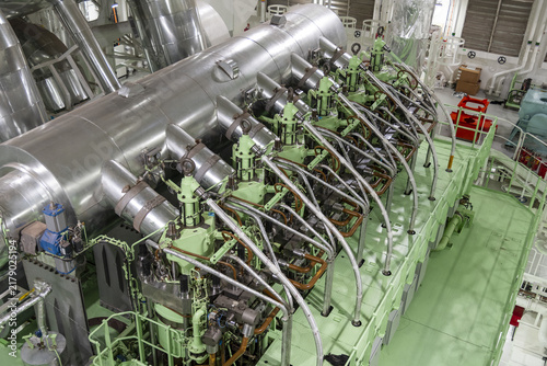 Close-up industrial photograph of the upper cylinder area of a methanol-fueled marine engine, showing exhaust valve housings, fuel injectors and numerous pipe connections.